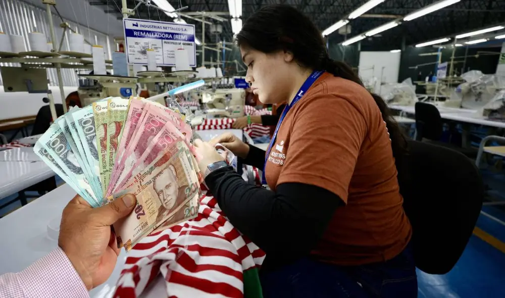 Trabajadora recibiendo el segundo para de la gratificación por Navidad. Foto: Composición LR/Andina.