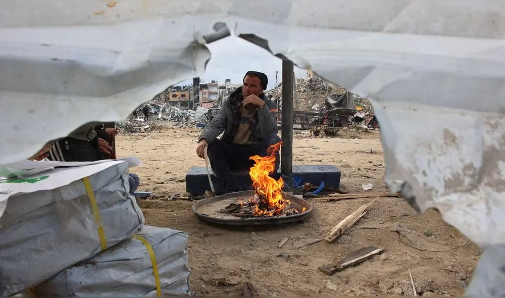 Un hombre enciende un fuego mientras los palestinos desplazados regresan a las zonas del norte de la Franja de Gaza (Jabalia) durante un alto el fuego. Foto: AFP. Un hombre enciende un fuego mientras los palestinos desplazados regresan a las zonas del norte de la Franja de Gaza (Jabalia) durante un alto el fuego. Foto: AFP.