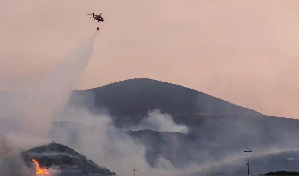 Hace dos días, un helicóptero descargó agua para combatir un incendio que afectaba la zona fronteriza en San Diego, California. Foto: AFP.