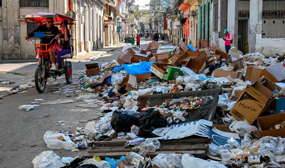 Los residentes locales caminan entre la basura acumulada en una calle de La Habana .