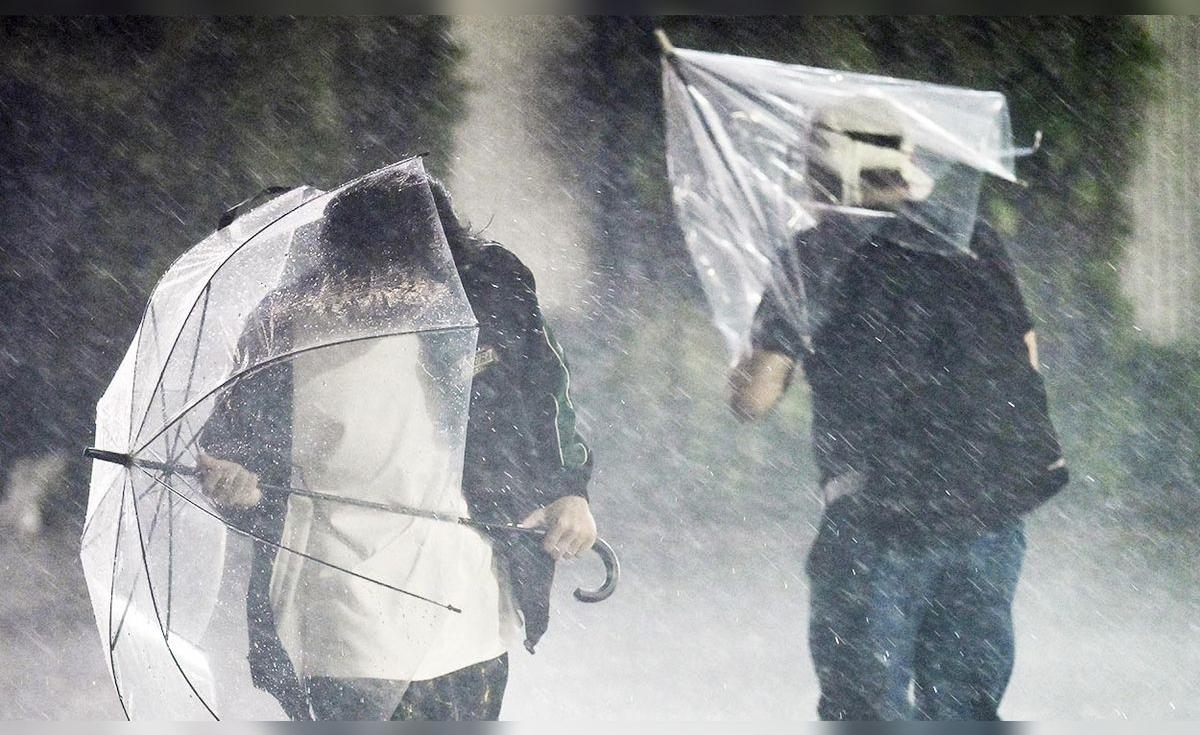 Dos personas caminan bajo una lluvia intensa con paraguas durante el tifón Dujuan en Japón, el 21 de septiembre de 2026