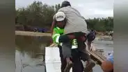 Policía carga a anciano para ayudarlo a cruzar puente de madera en Piura