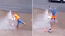 Trabajador de limpieza se para de manos para recoger una bolsa y evitar mojarse los zapatos en inundación