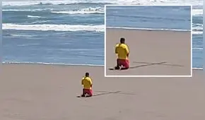 Salvavidas dibuja cruz en la arena y reza de rodillas en medio de pandemia