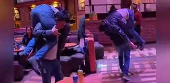 Joven ayuda a su amigo en estado de ebriedad y lo carga en su espalda para llevarlo a casa Joven ayuda a su amigo en estado de ebriedad y lo carga en su espalda para llevarlo a casa