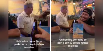 Hombre en estado de ebriedad se ve en un espejo y pelea con su propio reflejo en un bar Hombre en estado de ebriedad se ve en un espejo y pelea con su propio reflejo en un bar