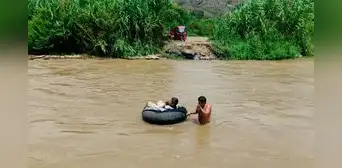 Niños y adultos mayores cruzan río sobre cámaras de llanta ante colapso de puente artesanal