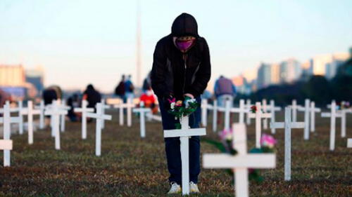 Un manifestante coloca flores en una cruz durante una protesta contra el presidente Jair Bolsonaro y en honor a las personas que murieron por la COVID-19. Foto: AFP. Brasil.