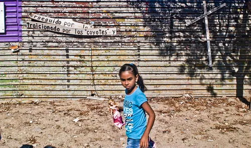 Niña camina junto a mensaje que cuestiona a traficantes de personas. Niña camina junto a mensaje que cuestiona a traficantes de personas.