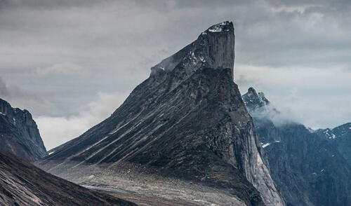 Si un objeto cayera desde la cima del acantilado occidental del Monte Thor se desplomaría 1250 m (4100 pies) antes de impactar contra algo. Foto: IFLScience. Esta montaña tiene la caída vertical más larga del mundo con más de 1.000 metros de altura y 105 grados de inclinación