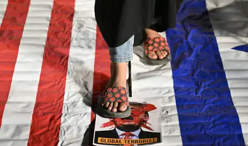 Un musulmán se yergue sobre un retrato de Donald Trump con la leyenda "Terrorista global" durante las celebraciones tras el alto el fuego de dos semanas.