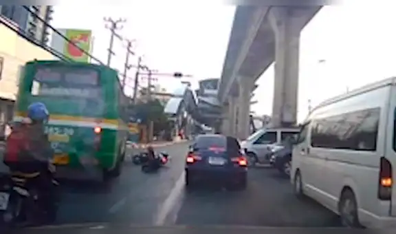 Repartidor de comida cae de motocicleta y su cabeza queda a pocos centímetros de autobús [VIDEO]