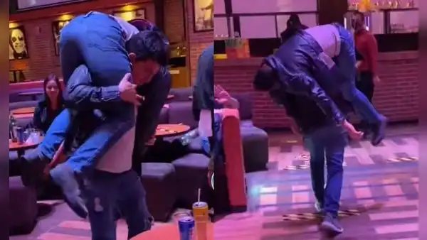 Joven ayuda a su amigo en estado de ebriedad y lo carga en su espalda para llevarlo a casa