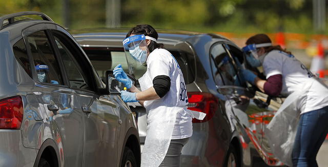 Los trabajadores médicos toman muestras para examinar el nuevo coronavirus COVID-19 de un visitante a un centro de pruebas de manejo en el Chessington World of Adventures Resort, en Chessington, suroeste de Londres, el 2 de mayo de 2020.