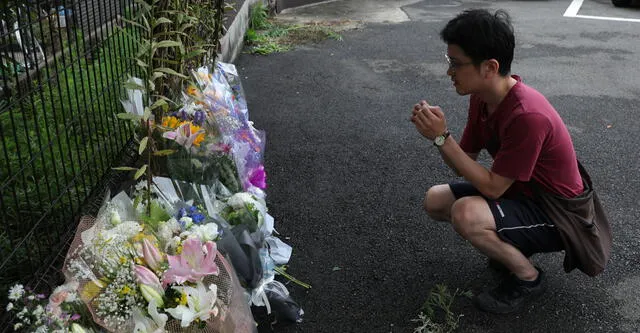 A man prays next to flowers and tributes laid at the scene where over 30 people died in a fire at the Kyoto Animation company building in Kyoto on July 19, 2019. - Details emerged July 19 of a horrifying inferno that tore through a Japanese animation firm and killed dozens, with people jumping out of the three-storey building and others trapped in a staircase unable to escape. (Photo by Buddhika Weerasinghe / AFP)