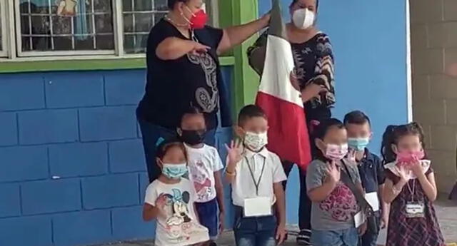 Niños mueven las manos a modo de "hola" cuando la maestra pidió que saluden a la bandera