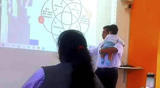  Profesor de Huaral ayuda a alumna en clase y carga a su bebé para que se concentre. Foto: Difusión   