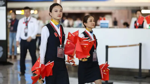Los miembros del personal pasan con banderas nacionales en el nuevo Aeropuerto Internacional Daxing de Beijing durante su primer día de operación en Beijing el 25 de septiembre de 2019.