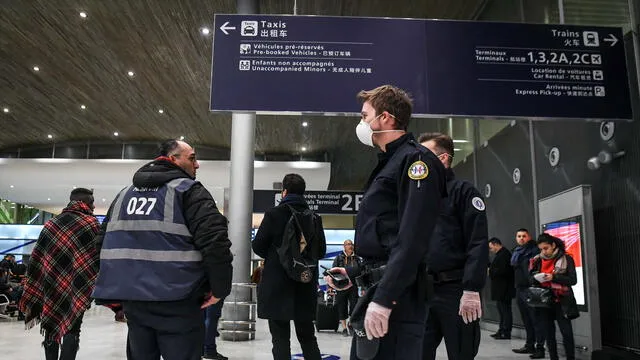 Policías con máscaras protectoras patrullan en la Terminal de llegada en el Aeropuerto Charles De Gaulle, en Roissy-en-France el 26 de enero de 2020.