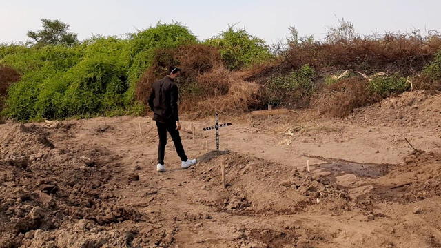 Joven observa la fosa donde fue enterrado su padre, una víctima más del COVID-19.