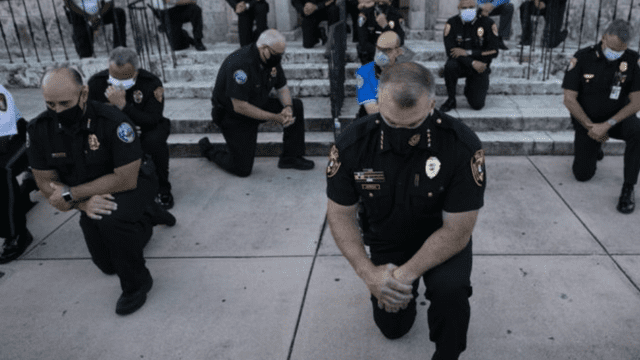 Agentes de la Asociación de oficiales del condado Miami-Dade recibieron de rodillas a los manifestantes y rezaron juntos. (Foto: AFP)