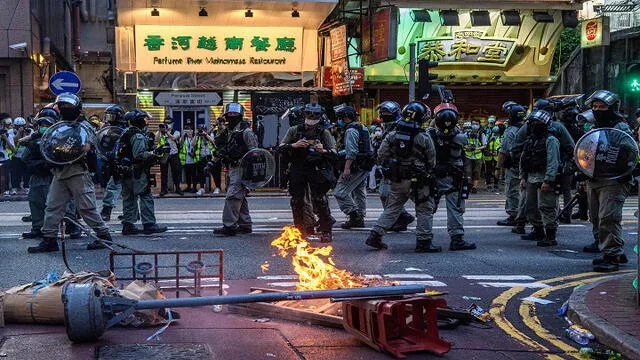 La policía pasa junto a una barricada incendiada creada por los manifestantes durante una manifestación contra una nueva ley de seguridad nacional en Hong Kong