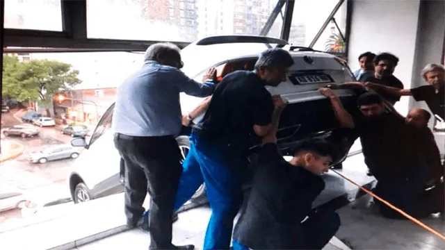 Auto queda colgando del segundo piso de concesionaria y causa pánico en los transeúntes [VIDEO]