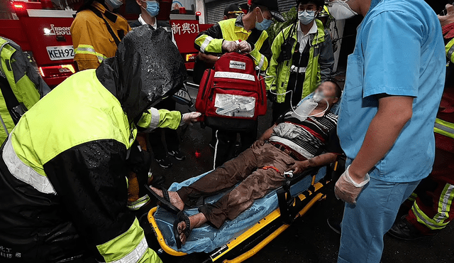 Un hombre rescatado siendo llevado en camilla mientras un equipo médico evalúa su estado. Foto: AFP