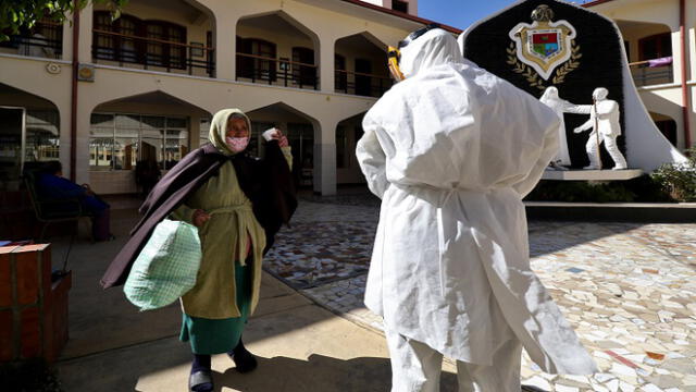 A health worker prepares to test an elderly woman for COVID-19 at the San Jose nursing home in Cochabamba, Bolivia, on July 17, 2020. - Ten elderly people of the San Jose nursing home died from the new coronavirus and 64 out of 100 tests done Friday turned out positive. (Photo by - / AFP)
