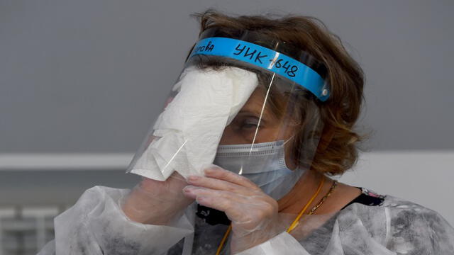 A member of a local electoral commission wearing protective gear - a measure against the spread of the coronavirus disease - wipes her face shield at a polling station during a nationwide vote on constitutional reforms in Saint Petersburg on July 1, 2020. (Photo by OLGA MALTSEVA / AFP)