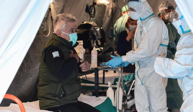 A patient sits in a tent to be tested for new coronavirus, at a temporary emergency structure set up outside the accident and emergency department, where any new arrivals presenting suspect symptoms are being  tested, at the Brescia hospital, Lombardy, on March 13, 2020. (Photo by Miguel MEDINA / AFP)
