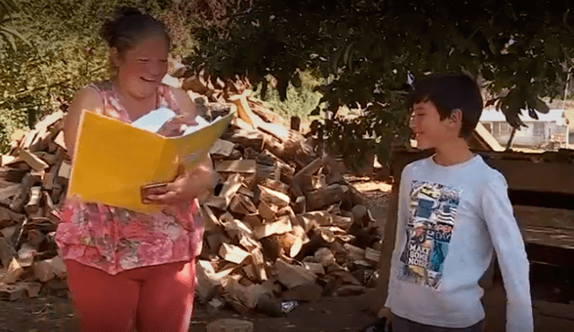 Una madre y su hijo reciben la guía de estudio durante la cuarentena. (Foto: Captura)