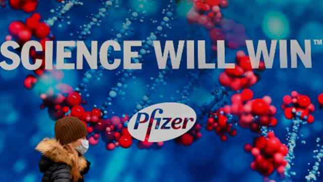 Una persona que lleva una mascarilla protectora pasa por delante de Pfizer Inc. Foto: AFP
