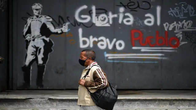 A man wearing a face mask walks past a graffiti reading �glory to the brave people� in downtown after the government eased a nationwide lockdown as a preventive measure against the COVID-19 coronavirus, in Caracas, on July 14, 2020. (Photo by Federico PARRA / AFP)
