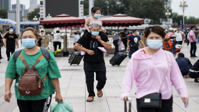 People wearing face masks arrive at Beijing Railway Station in Beijing on August 19, 2020. (Photo by NOEL CELIS / AFP)