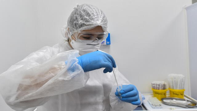 A member of the medical staff at Gemotest, wearing personal protective equipment (PPE) works with a saliva sample at the COVID-19 testing facility in Moscow on May 2, 2020, amid the spread of the novel coronavirus, COVID-19. - Russia on May 2, 2020, reported its largest increase in coronavirus cases with the new infections rising by nearly 10,000 in a single day. (Photo by Vasily MAXIMOV / AFP)