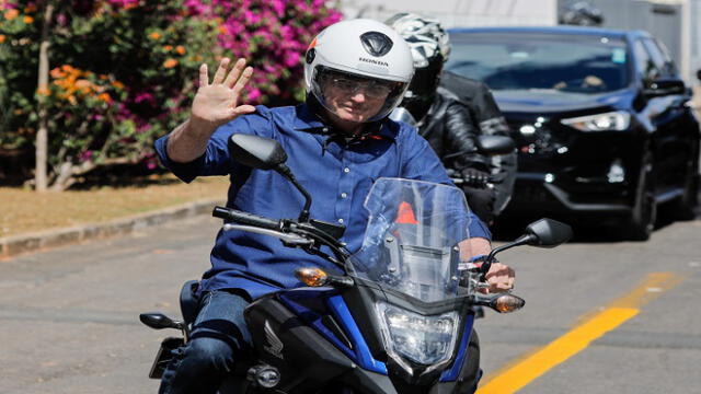 Brazilian President Jair Bolsonaro waves as he takes a ride and has his motorcycle's engine overhaul after he announced he tested negative for COVID-19 more than two weeks after being diagnosed, in Brasilia, on July 25, 2020, during the novel coronavirus pandemic. (Photo by Sergio LIMA / AFP)