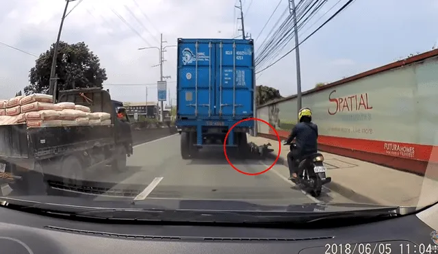 Youtube: Motociclista es aplastado por un tráiler, pero se para como si nada [VIDEO]