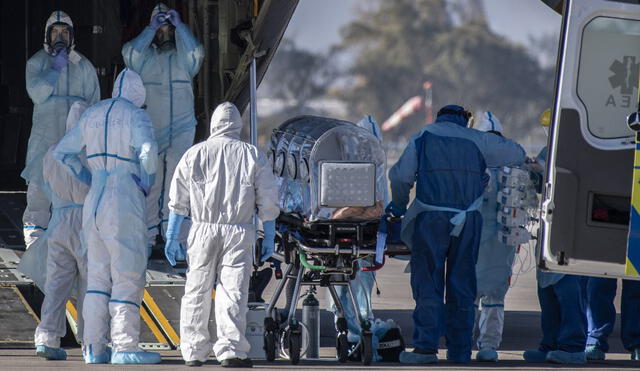 Health workers move a COVID-19 infected patient to a C-130 Hercules, to be taken to the city of Concepcion, at a Chilean Air Force base in Santiago, Chile, on May 24, 2020. - Patients infected with COVID-19 are taken to other cities in the country in order to free up space in the intensive care units of hospitals in Santiago. (Photo by Martin BERNETTI / AFP)