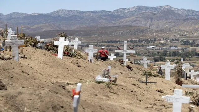 A musician walks between graves at the Municipal Cemetery #13 in Tijuana, Baja California state, Mexico on June 9, 2020, amid the COVID-19 pandemic. (Photo by Guillermo Arias / AFP)