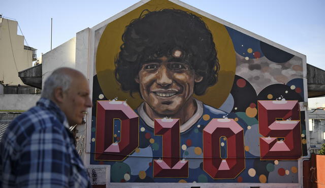 The former director of Argentinos Juniors sports club and owner of the 'Casa de Dios' (House of God) museum, Alberto Perez, walks past a mural of Argentine football star Diego Maradona in Buenos Aires, on June 27, 2018. - 'Casa de Dios' is located at the house where Maradona used to live (1978 - 1980) when he played for Argentinos Juniors in La Paternal neighborhood. (Photo by EITAN ABRAMOVICH / AFP)