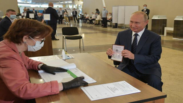Russian President Vladimir Putin shows his passport to a member of a local electoral commission as he arrives to cast his ballot in a nationwide vote on constitutional reforms at a polling station in Moscow on July 1, 2020. (Photo by Alexei Druzhinin / SPUTNIK / AFP)