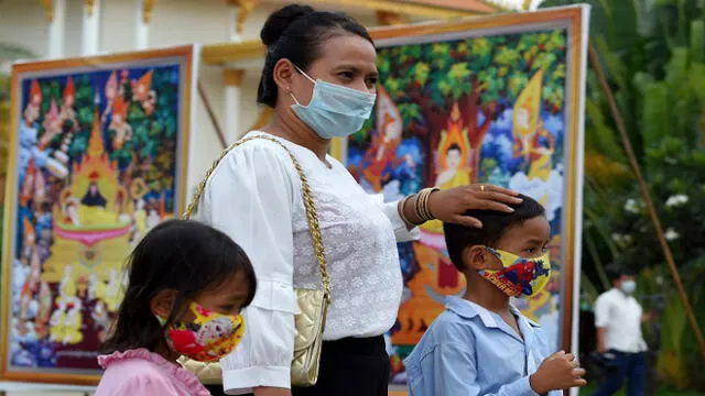A woman and her children, wearing face masks as a preventive measure against the spread of the COVID-19 novel coronavirus, attend the Visak Bochea Buddhist celebration at a pagoda in Phnom Penh on May 6, 2020. - Buddhists commemorate the birth of Buddha, his attaining enlightenment and death on the day of the full moon in the month of May, which falls on May 6 this year. (Photo by TANG CHHIN Sothy / AFP)