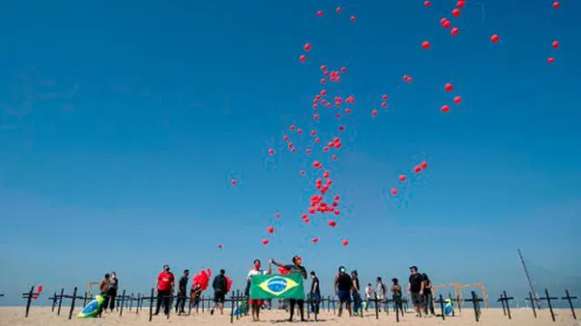 Varias personas se presentan en una de las playas más conocidas de Brasil para rendir homenaje a los fallecidos por coronavirus.Foto: AFP.