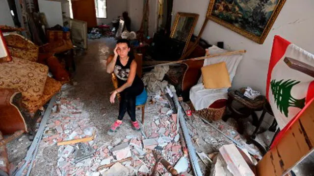 Una mujer sentada entre los escombros de su casa en la capital libanesa, Beirut, el 6 de agosto de 2020. Foto: AFP.