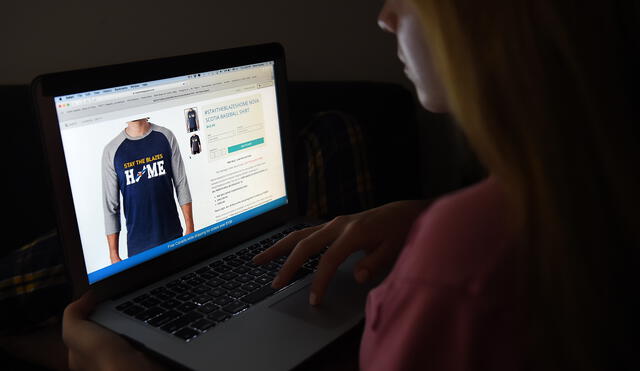 In this photo illustration, a person looks at a computer displaying a "Stay the blazes home" Nova Scotia baseball shirt on a website,  April 16, 2020, in Arlington, Virginia. - "Stay the blazes home": the colloquial expletive-laced call by the premier of Canada's Atlantic coast province of Nova Scotia has become a rallying cry in the coronavirus pandemic fight.The comment during a televised COVID-19 briefing last week by Liberal Premier Stephen McNeil, exasperated by people who were ignoring a ban on public gatherings to stroll crowded beaches or go to parties, has since appeared on t-shirts and mugs. (Photo by Olivier DOULIERY / AFP)