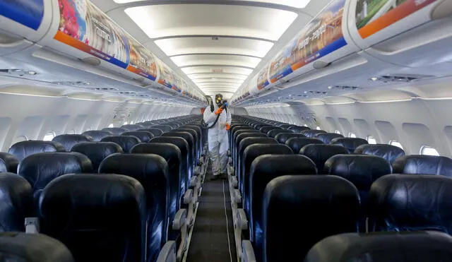 An Israeli worker in full hazmat suit sprays disinfectant in the cabin of an Israir Airlines Airbus A320 airplane, at the Ben Gurion International Airport near the central Israeli city of Tel Aviv, on June 14, 2020, amid the novel coronavirus pandemic. (Photo by GIL COHEN-MAGEN / AFP)