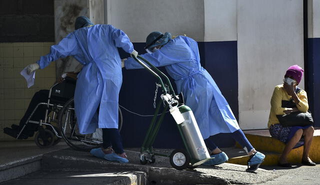 Trabajadores de la salud llevan a una persona,con oxígeno y en silla de ruedas, hacia las instalaciones de un hospital. Foto: AFP.