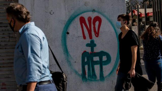 Personas pasan por un graffiti contra la Administración del Fondo de Pensiones (AFP) en Santiago. Foto: AFP.