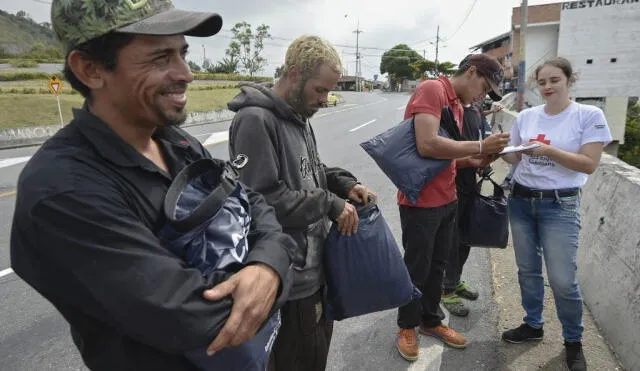 Venezuelan migrants receive bags from members of the Red Cross in Bucaramanga, Colombia, on December 17, 2019. - Venezuelan migrants in Colombia undertake a round trip to their country with the desire to spend Christmas at home. (Photo by Juan BARRETO / AFP)